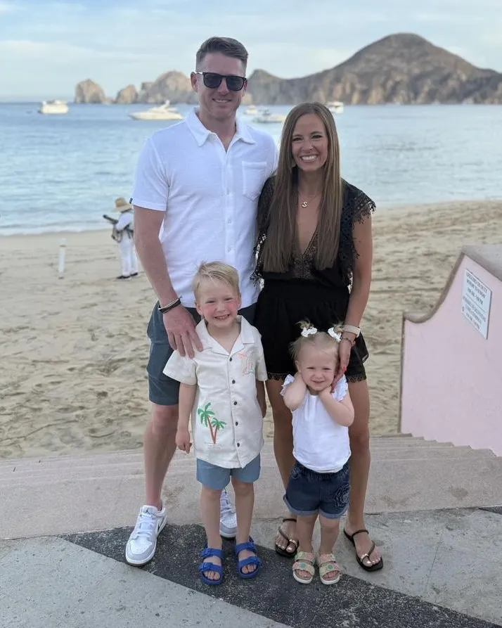 Our family of four on the beach, all smiling, with the kids in front